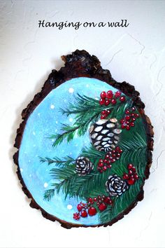 a piece of wood with pine cones and berries painted on it, sitting on a marble surface