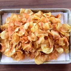 a metal pan filled with potato chips on top of a wooden table