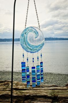 a wind chime hanging from a pole next to the ocean on a cloudy day