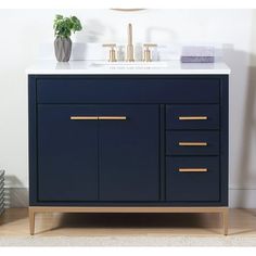 a bathroom vanity with two sinks and gold handles on the top, against a white wall