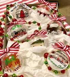 christmas ornaments are in a box with red and green ribbon around them on the table