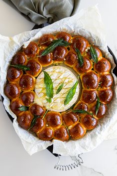 a pizza covered in meatballs and cheese on top of wax paper with green leafy garnish