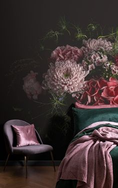 a bed with pink and purple flowers on the headboard next to a green chair