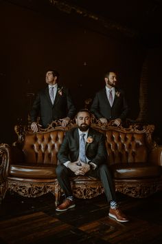 three men in suits are sitting on a couch