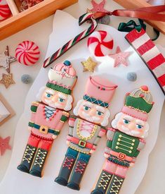 three nutcrackers are sitting next to candy canes