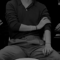 black and white photograph of a man sitting on a stool with his arms folded out