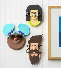 three paper cutouts are hanging on the wall next to a framed photo and sunglasses