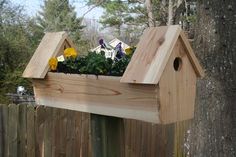 a wooden birdhouse with flowers growing in it