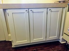 a kitchen with white cabinets and brown flooring