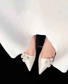 a woman's feet wearing white shoes with flowers on the toe and bottom of her shoe