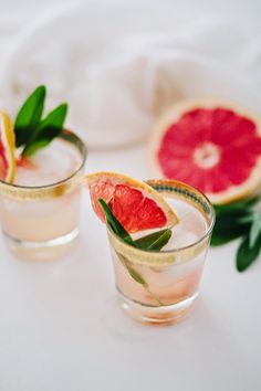 two glasses filled with watermelon and garnish sitting on top of a table