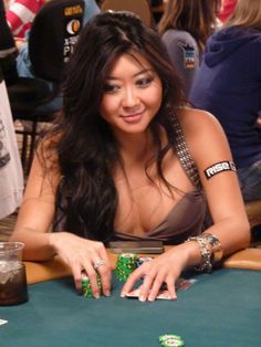 a woman sitting at a poker table with her hands on the cards and chips in front of her