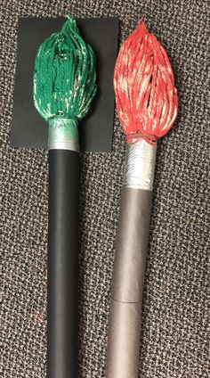 two different colored yarns are on top of black poles with red and green ends