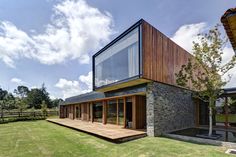 a modern house with large windows and wooden decking on the grass area in front of it