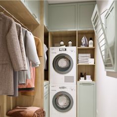 a washer and dryer in a room with clothes hanging on the rack next to it