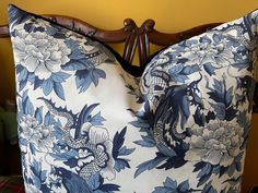 a blue and white flowered pillow on a wooden headboard next to a yellow wall