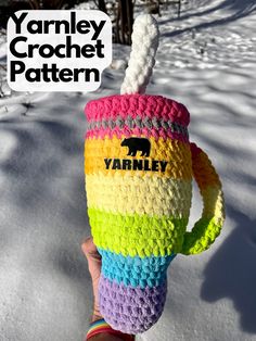 a person holding up a crocheted cup in the snow