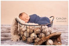 a baby sleeping in a basket full of baseballs