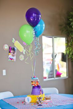 a table topped with balloons and confetti on top of a blue table cloth