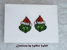 a pair of beaded christmas earrings with the grin face on it's ear