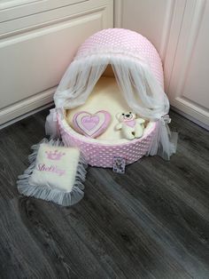 a pink and white baby's bed with a teddy bear in it