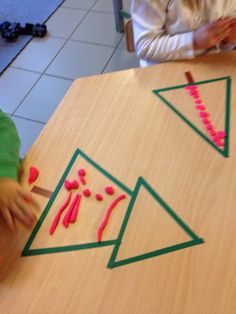 two children are sitting at a table making triangle shapes