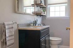 a white toilet sitting next to a sink in a bathroom under a mirror above a window