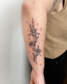 a person with a tattoo on their arm holding a knife and flowers in the other hand