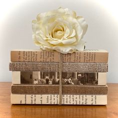 three books stacked on top of each other with a white flower sitting on top of them