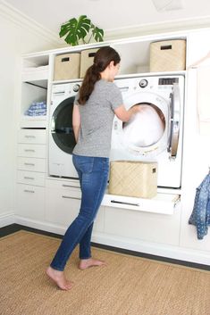 a woman is standing in front of the washer and looking into the dryer