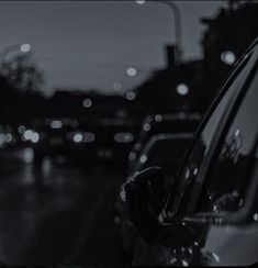 the back window of a car on a city street at night with lights in the background