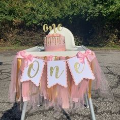 a pink and gold 1st birthday cake table