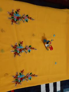 a yellow table cloth with flowers on it and some pins attached to the side of it