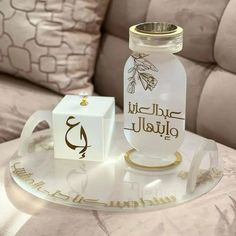 a glass bottle sitting on top of a table next to a small white box with gold lettering