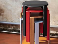 three stools stacked on top of each other in front of a wall and floor