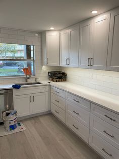 a kitchen with white cabinets and wood floors