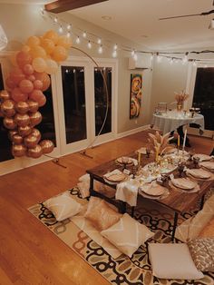 a dining room table set for a party with balloons in the air and decorations on the floor