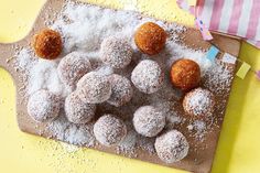 powdered sugar covered donuts on a cutting board next to a pink and white striped napkin