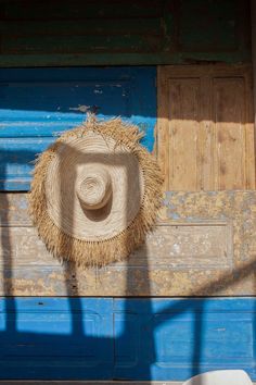 Moroccan straw hat with raffia fringe displayed on a wall made of aged wood shutters. Distressed Shutters, Thinking Outside The Box