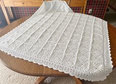 a white crocheted blanket sitting on top of a wooden table