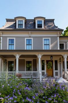 a large house with lots of windows and flowers in the front yard