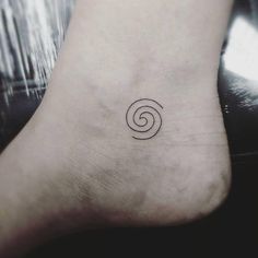 a small tattoo on the foot of a person with a spiral symbol in it's center