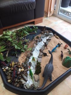 a tray filled with plastic dinosaurs and rocks