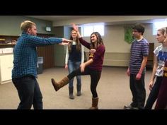 a group of young people standing around each other in a room with one man holding his leg up