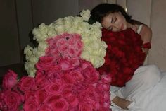 a woman laying on top of a bed covered in lots of pink and white roses