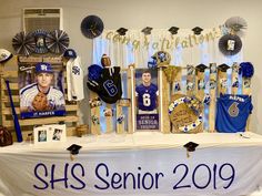 a table topped with pictures and decorations for a baseball game in blue, white and gold