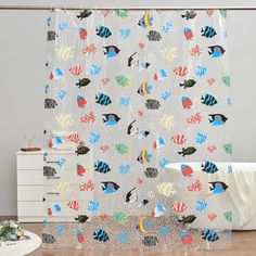 a shower curtain with fish on it in a bathroom next to a dresser and drawers