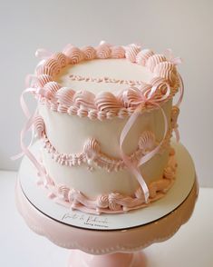 a white cake with pink icing and ribbons