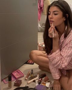 a woman is sitting on the floor with makeup and brushes in front of her face