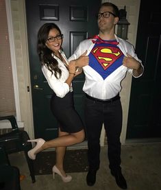 a man standing next to a woman in front of a door wearing a superman shirt